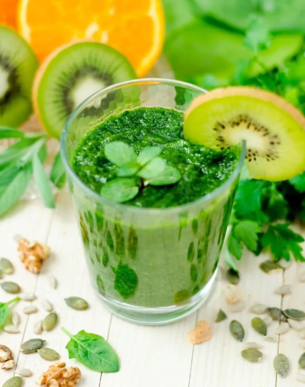 Green smoothie in a glass with leafy greens and seeds
