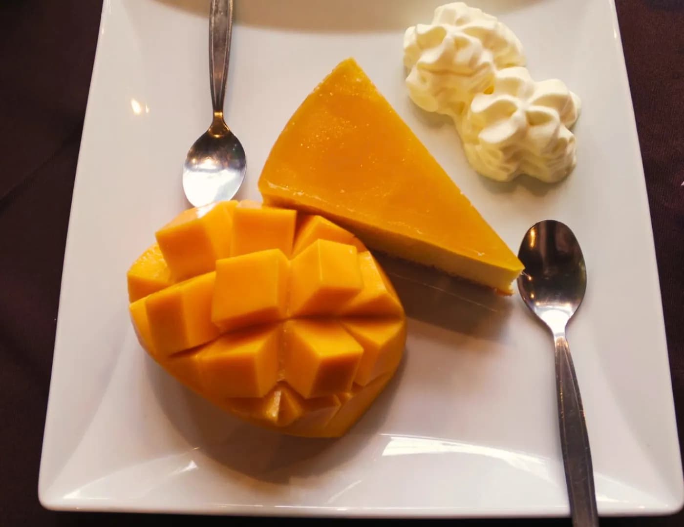 Plate with carved cubed mango, a wedge of mango cheesecake and a whipped-cream rosette
