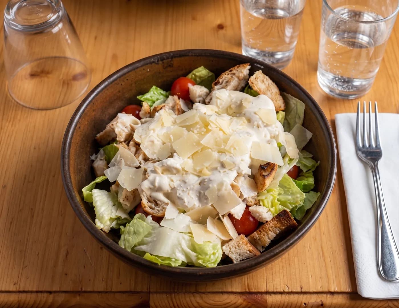 Bowl of Caesar-style salad with romaine, croutons, creamy dressing and shaved parmesan