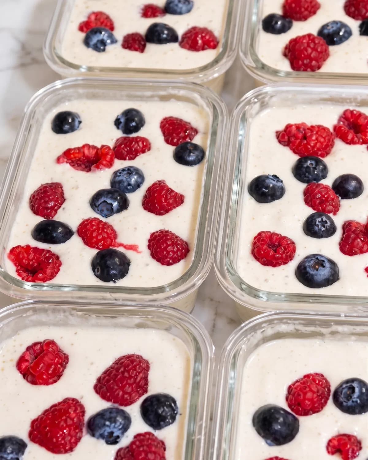 Meal-prep tubs of yoghurt topped with raspberries and blueberries